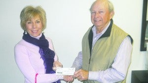 FIGHTING HUNGER: John Tunstall (right), president of the Down East Seniors club, presents a donation from the club to Debbie Adams, interim executive director of Eagle's Wings food pantry. One of the primary functions of the Down East Seniors is to aid local charities. CONTRIBUTED