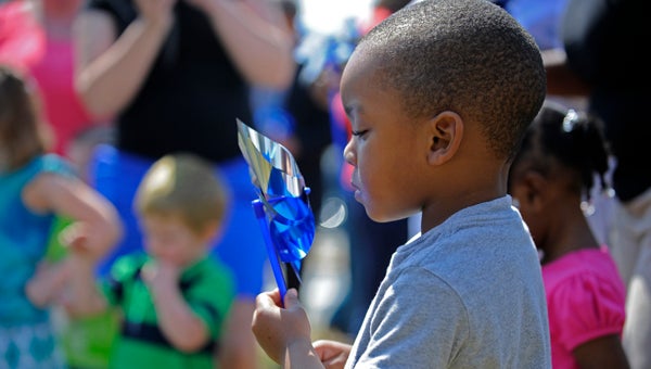 CUTLINE:  CONTEMPLATING PINWHEELS: Juelz Brown, who attends Just Toddlers Daycare in Washington, studies his reflection in a blue and silver pinwheel. Juelz took part in building a pinwheel garden at corner of Main and Gladden streets Thursday, an annual event that brings awareness to child abuse. 