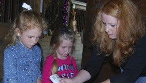 BARN OF BOOS: Leanna Hudson (left) and Chloe Alligood work on a skeleton craft with assistance from Misty Lanning.