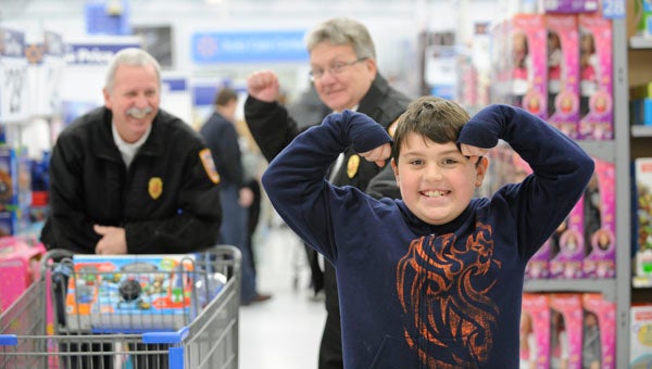 VAIL STEWART RUMLEY  | DAILY NEWS ON TOP OF THE WORLD: Monday, this happy boy celebrated his Wal-Mart shopping spree as Washington Fire Marshal Mark Yates and Fire Chief Robbie Rose looked on. Fourteen children from the non-profit ExCEL were invited to “Shop with a Safety Officer” as part of Washington Police and Fire Services’ community outreach program. For more photos of the event, see page 10 of today’s Washington Daily News. 