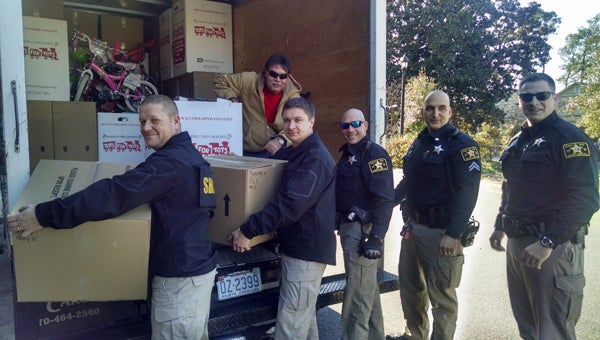 RICH MORIN | CONTRIBUTED CHRISTMAS HAUL: John Robinson, PotashCorp organizer (top), and (left to right) Beaufort County Sheriff’s Office’s Investigator Jeremy Landek, Lt. Wesley Waters, Deputy Mike Lore, Deputy Joe Kolibabek and Deputy Jim Mills unload employee donations from a fully-loaded truck to Toys for Tots.  