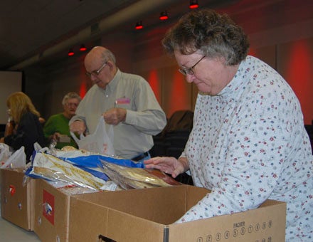 KEVIN SCOTT CUTLER | DAILY NEWS SORTING: Susan Cox and Wesley Fredericks (in background) are among the volunteers who pitch in during the church's food distribution. 