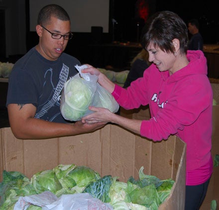 KEVIN SCOTT CUTLER | DAILY NEWS TEAMWORK: Shane Tyson and Tracy Thompson work together bagging cabbage, which was later distributed to families in need. 