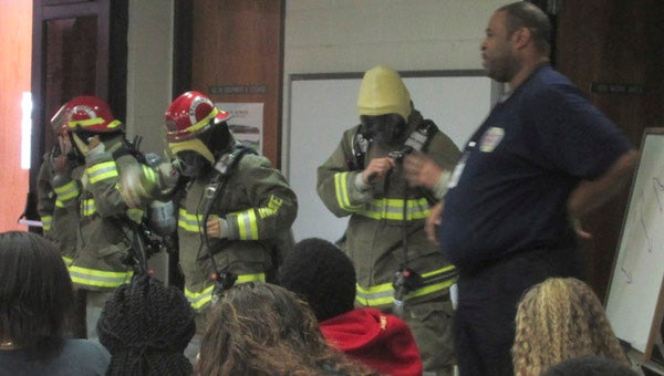 S.W. SNOWDEN ELEMENTARY SCHOOL FIRE ACADEMY: Southside High School’s Fire and EMT Academy students visited with S.W. Snowden’s middle school students to engage and educate about the program now in its second year. Lead instructor Otis Harrell lead the demonstration that included student testimonials, course of study, gateway examples for employment in the health fields and use of equipment. Academy advantages for students include college tuition savings, networking opportunities, work-based learning, EMT Basic Certification and community service activities. Pictured: Southside High School Fire and EMT Academy students exhibit the use of firefighting gear as Harrell narrates specific functions and technology. 