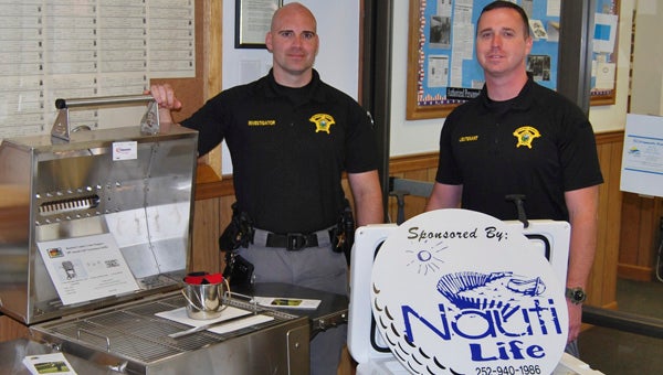 Kevin Scott Cutler | Daily News CRIME STOPPERS RAFFLE: Investigator Jonathan Fowler (left) and Lt. Kelly Cox of the Beaufort County Sheriff's Office show off a stainless steel grill and Yeti cooler, two prizes up for grabs in this year's Crime Stoppers raffle. Tickets are now available and prizes will be awarded April 19. 