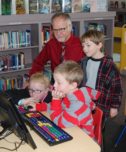 TECHNOLOGY: Library staff member Terry Rollins assists a trio of young patrons.